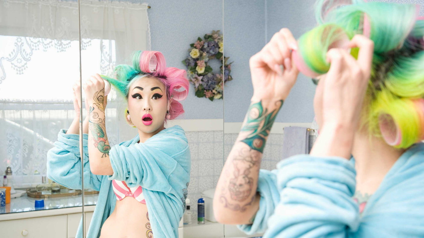 Pearl Beauty Supply woman pink and green hair looking at mirror